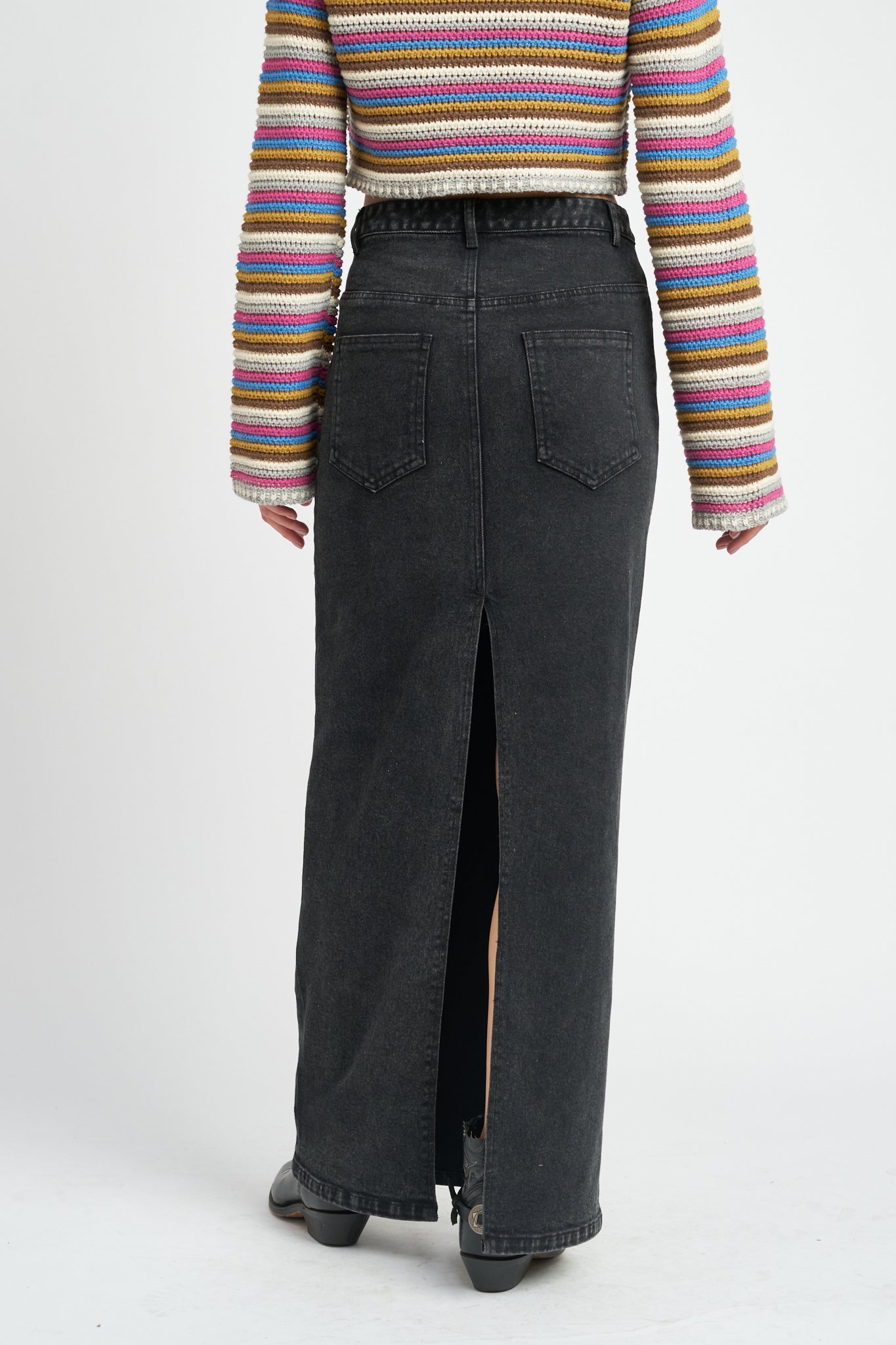 A model wearing a long black denim pencil skirt backside view. 