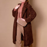 Model in a brown faux fur coat and turtle neck wearing a Melie Bianco  taupe crossbody bag.
