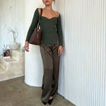 A model wearing a espresso recycled vegan leather shoulder bag against a white wall. 