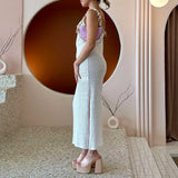 A model wearing a lilac crochet straw top handle bag with a seashell detail along the handle.