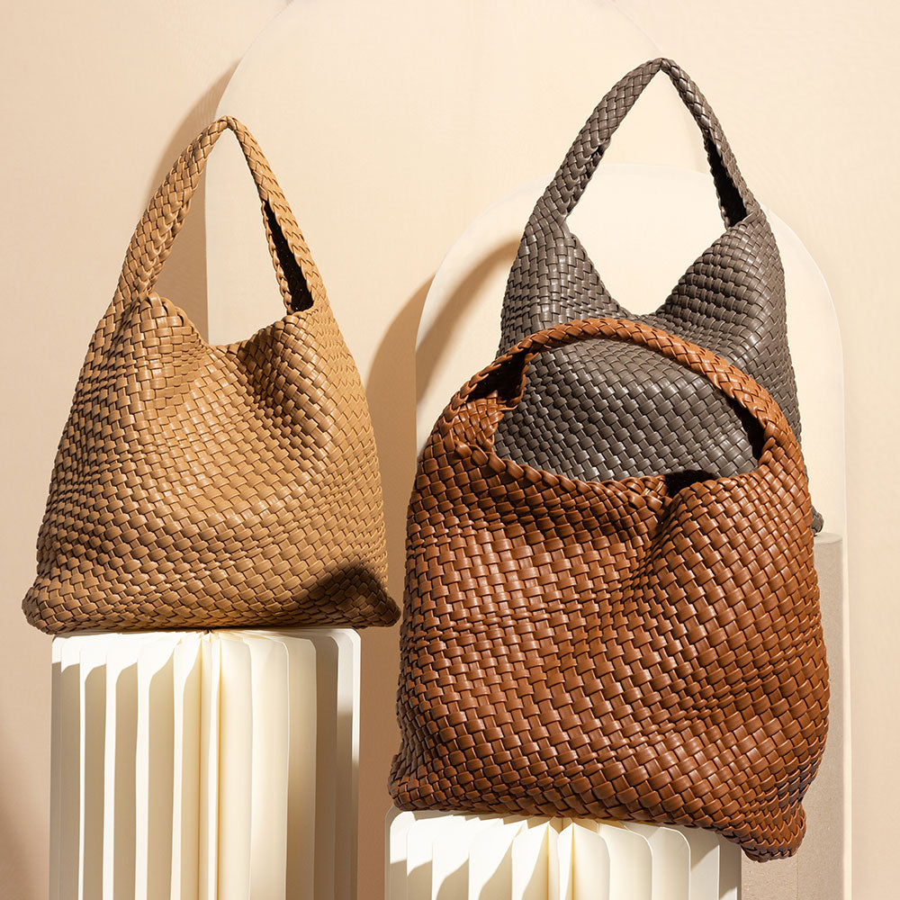 A still image of three woven vegan leather shoulder bags against a cream wall. 