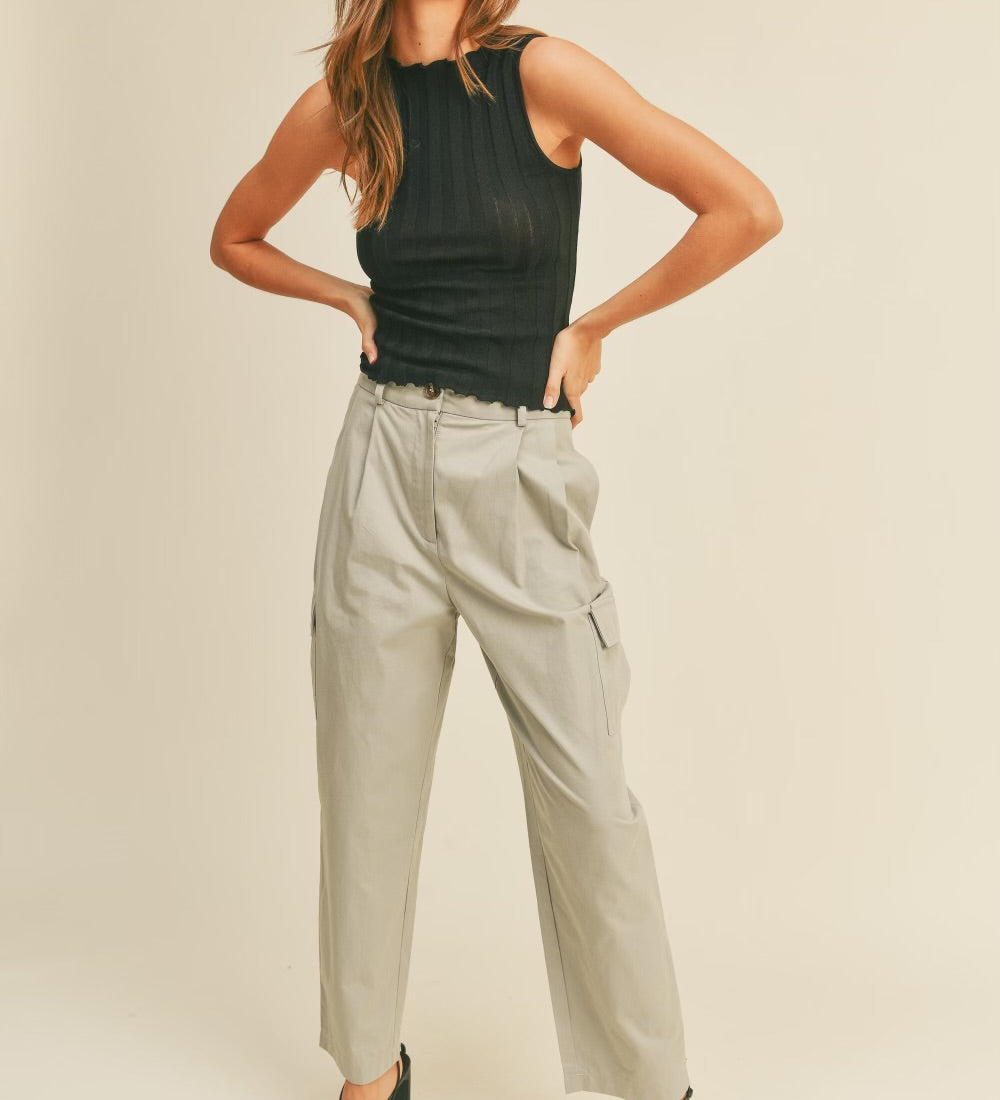 A model wearing a beige high rise cargo pant against a tan wall. 