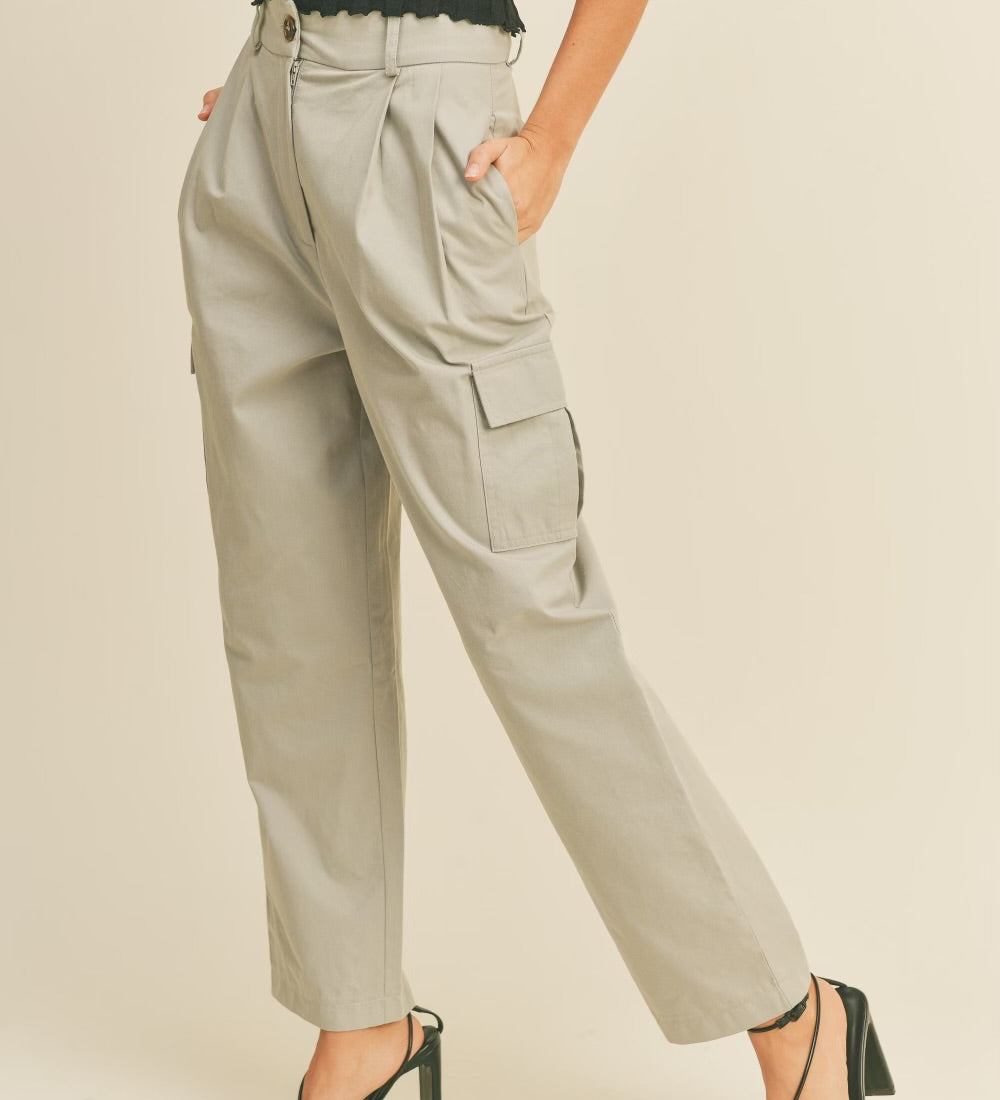 A model wearing a beige high rise cargo pant against a tan wall.