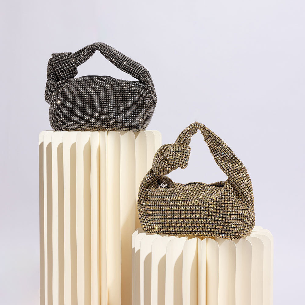 A still image of two small crystal encrusted top handle bags against a white background.