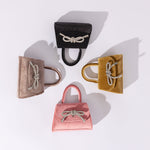 A still image of four mini velvet top handle bags with a silver encrusted bows against a white background,