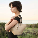 Woman holding a beige handbag in an outdoor setting