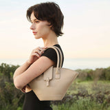 Woman holding a beige handbag in an outdoor setting