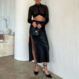 A model wearing a small black recycled vegan leather top handle bag with silver hardware against a white wall. 