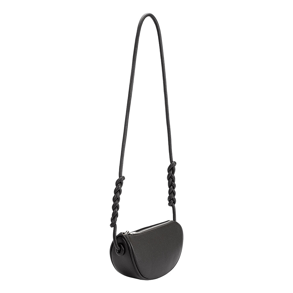 A small black crescent shaped vegan leather crossbody bag with a braided strap. 