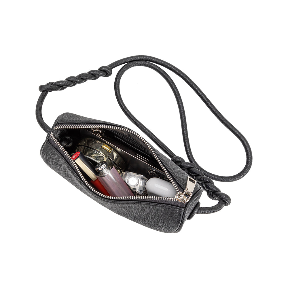 An inside view image of a small crescent vegan leather crossbody bag with a phone, makeup, and earbuds inside. 