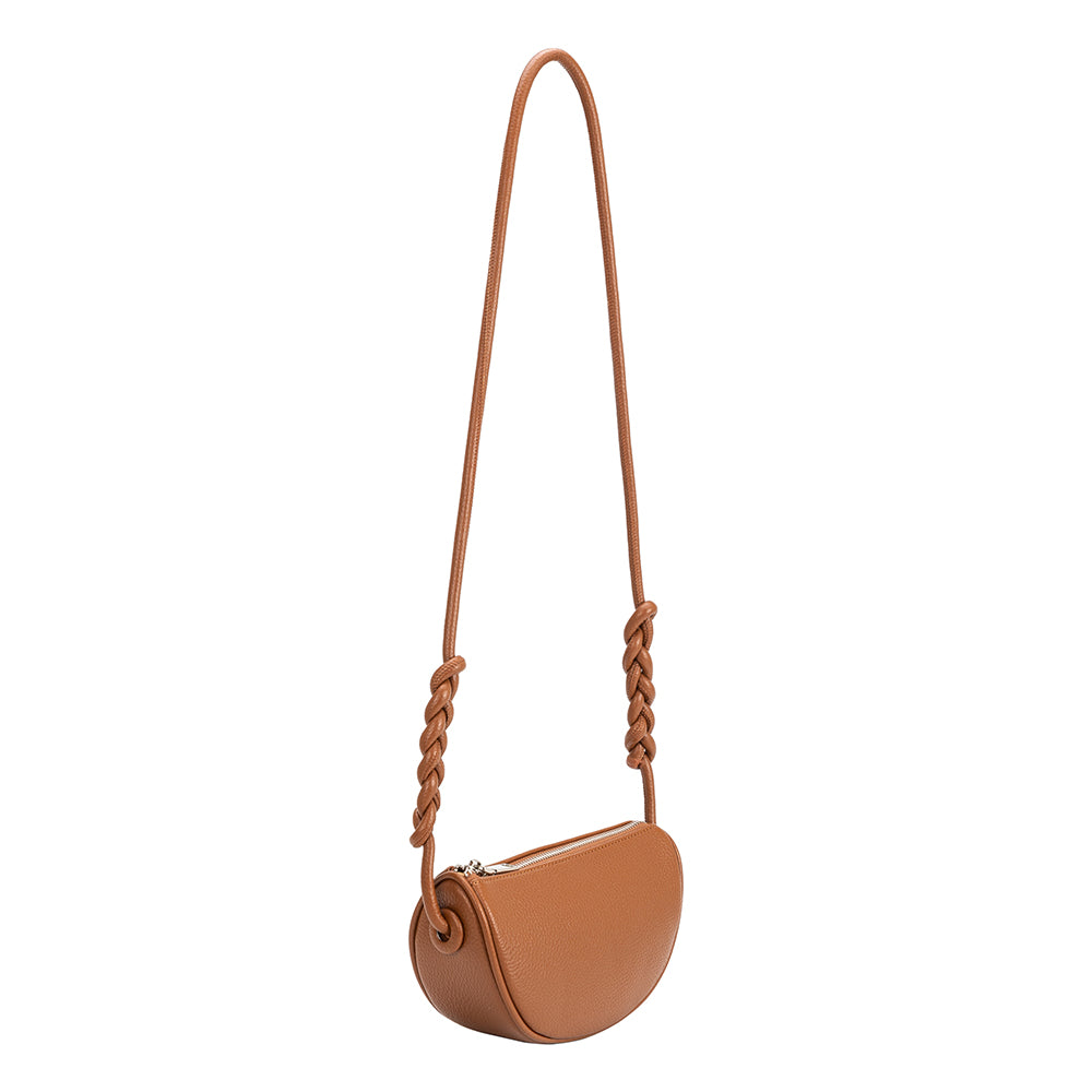 A small saddle crescent vegan leather crossbody bag with braided strap.