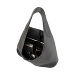 An inside view image of a large black shoulder bag with a laptop, phone, and charger inside. 