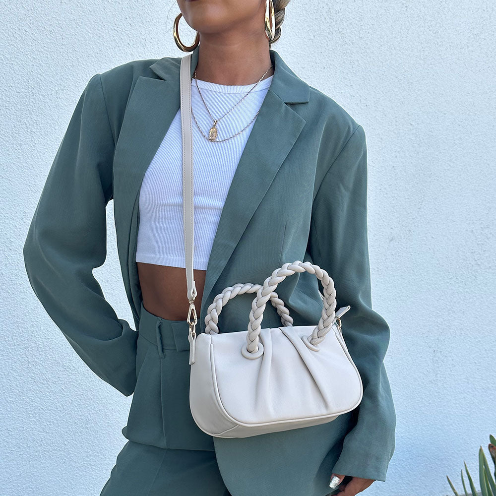 A model wearing a small recycled vegan leather crossbody bag with twisted handle.