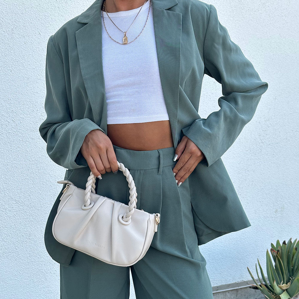 A model holding a small recycled vegan leather crossbody bag with twisted handle. 