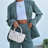 A model holding a small recycled vegan leather crossbody bag with twisted handle. 