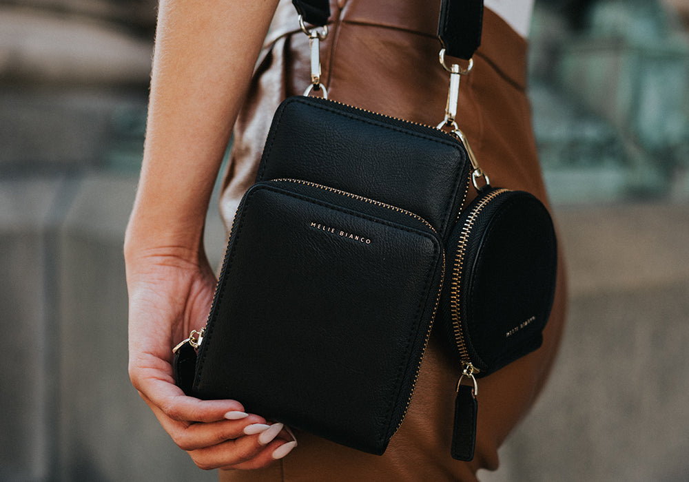 A model wearing a small vegan leather crossbody bag with a coin pouch.