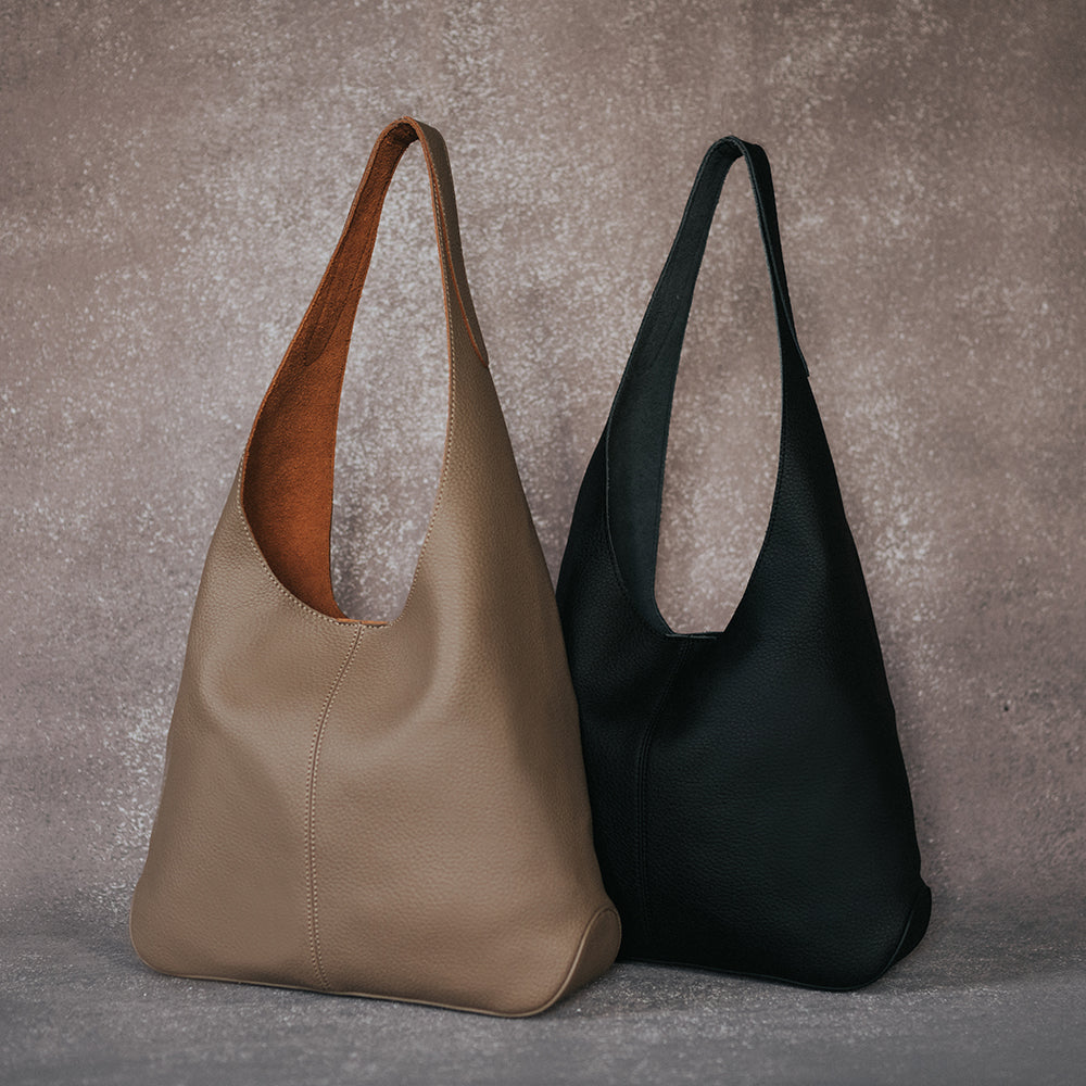 A still image with two large recycled vegan leather shoulder bags against a brown background. 