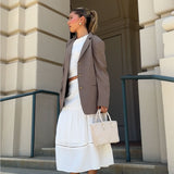 A model wearing a small woven vegan leather crossbody bag outside on stairs. 