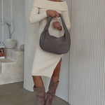 Video of a model wearing a recycled vegan leather shoulder handbag against a white wall. 