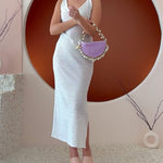 Video of a model wearing a small lavender crochet straw top handle bag with a seashell detail along the handle.