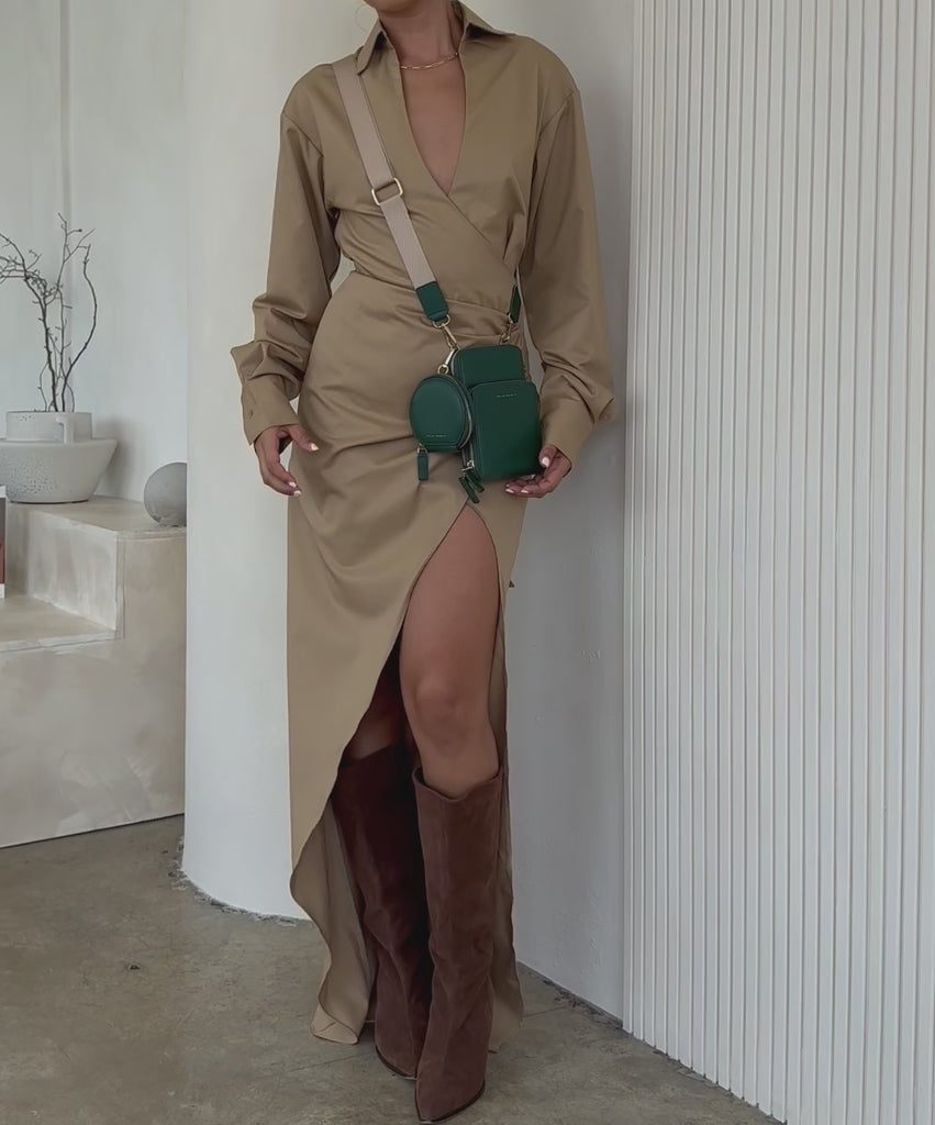 Video of a model wearing a small vegan leather crossbody bag against a white wall. 
