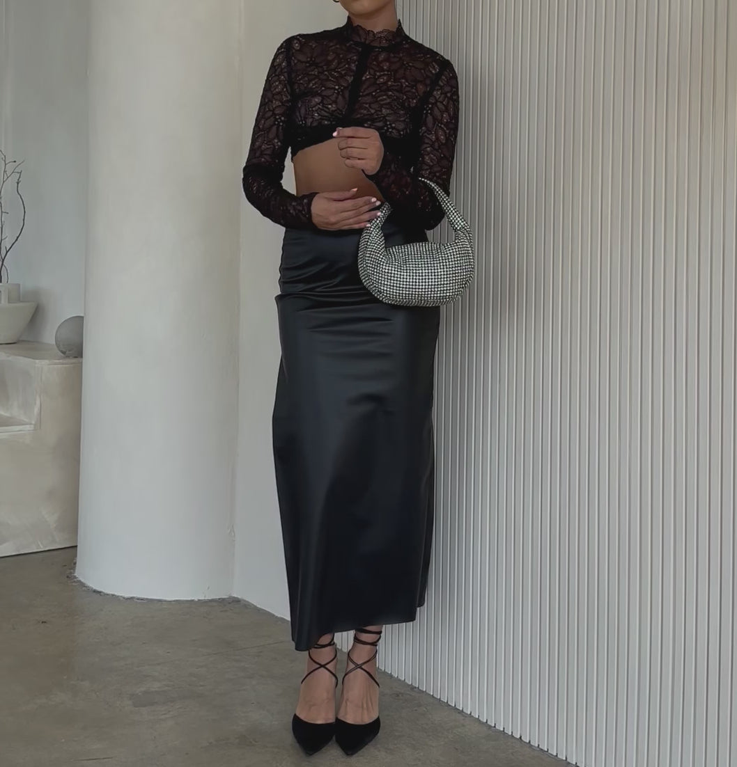 Video of a model wearing a small crystal encrusted crossbody bag against a white wall. 