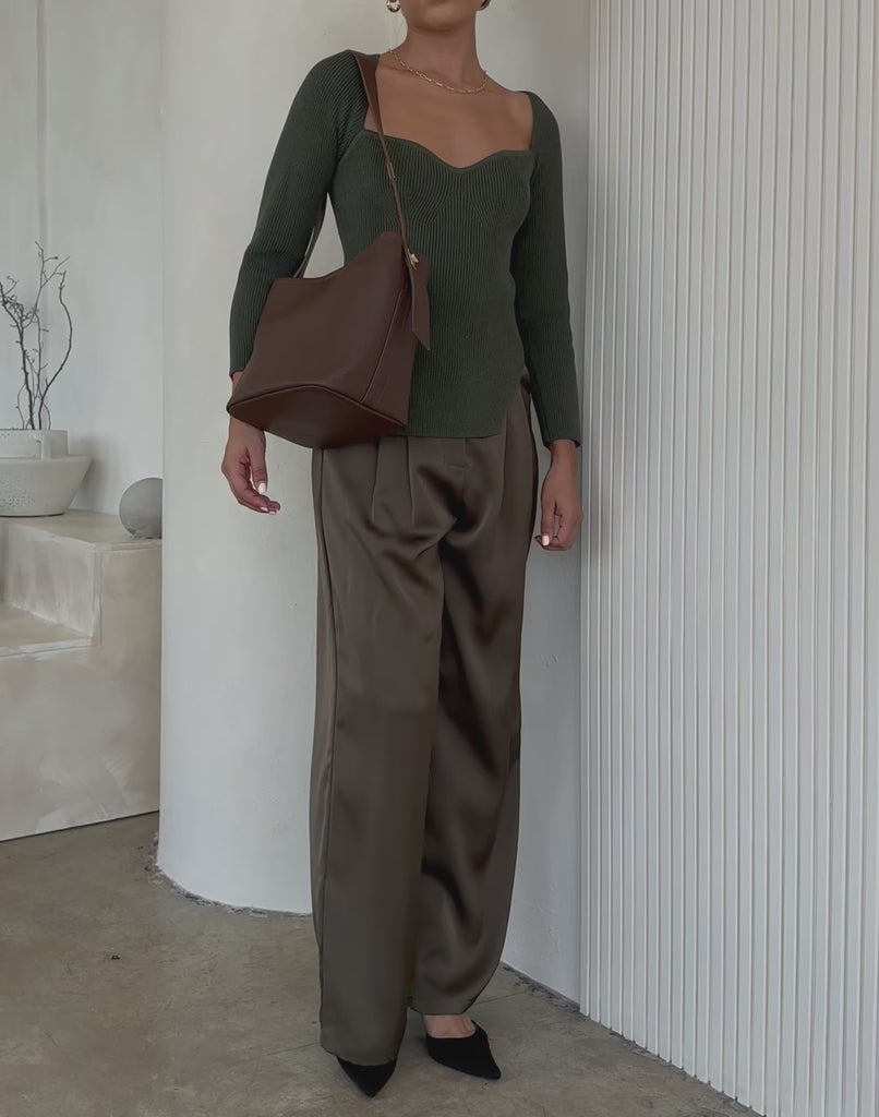 Video of a model wearing an espresso recycled vegan leather shoulder bag against a white wall. 