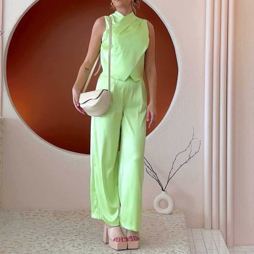 Video of a model wearing a nude vegan leather crossbody bag with a wavy front flap closure.