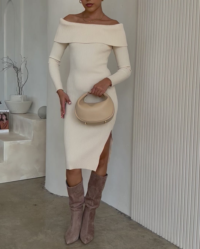 Video of a model wearing a crescent vegan leather crossbody bag with silver hardware against a white wall. 