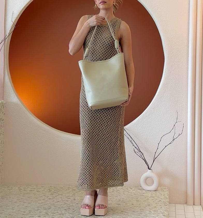 Video of a model wearing a large vegan leather tote bag with a knotted handle.
