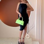 Video of a model wearing a small lime vegan leather rectangle shaped top handle bag.