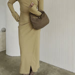 Video fo a model holding a suede recycled vegan leather top handle bag with a knot.