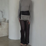 Video of a model wearing a small quilted pattern clutch with silver chain against a white wall. 