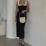 Video of a model wearing a nude vegan leather crossbody handbag against a white wall.