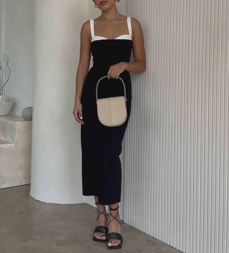 Video of a model holding a ivory crossbody handbag with silver handle.