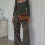 Video of a model wearing a saddle recycled vegan leather crossbody handbag against a white wall. 
