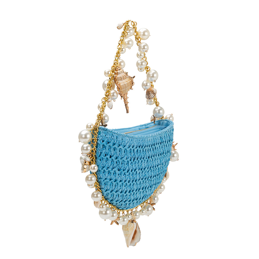 A small blue crochet straw top handle bag with seashell details along the handle