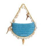 A small blue crochet straw top handle bag with seashell details along the handle.