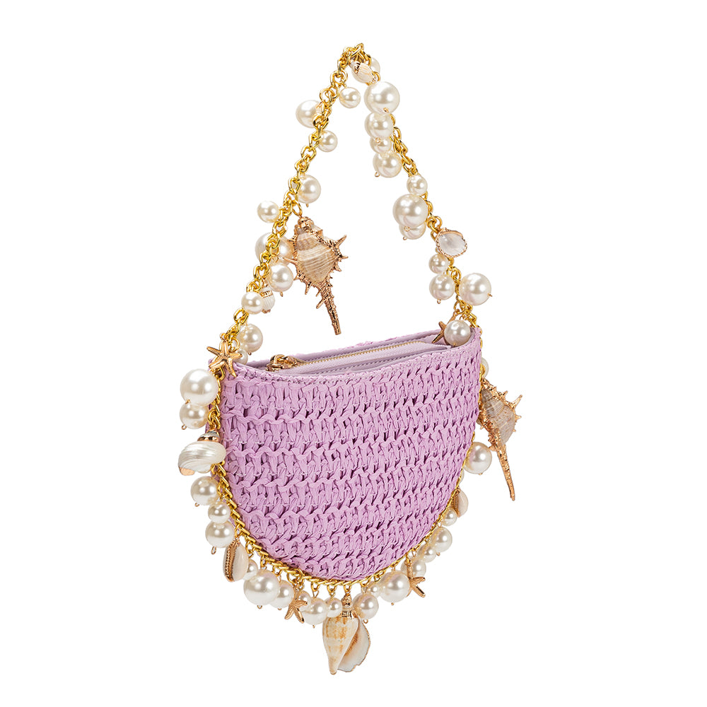 A small lavender crochet straw top handle bag with a seashell detail along the handle.