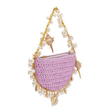 A small lavender crochet straw top handle bag with a seashell detail along the handle.