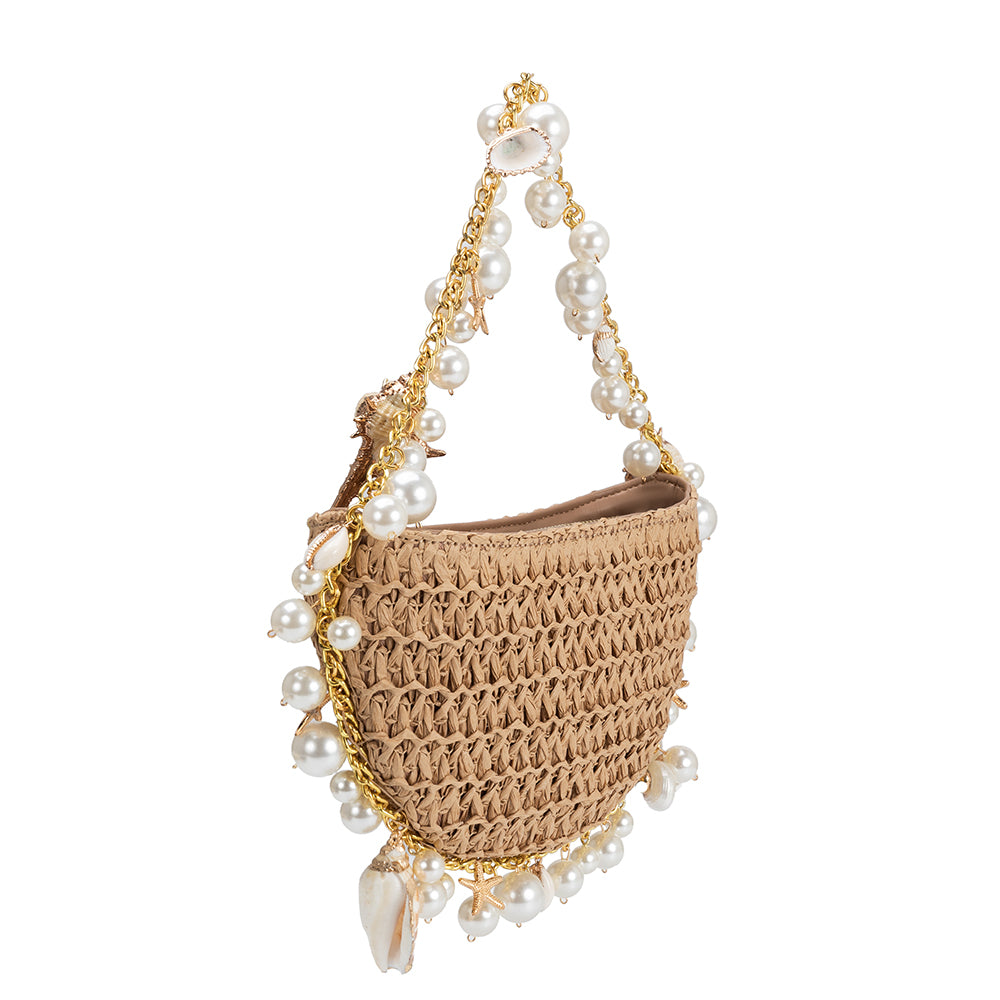 A small sand crochet straw top handle bag with seashell details along the handle.