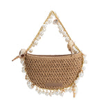 A small sand crochet straw top handle bag with seashell details along the handle