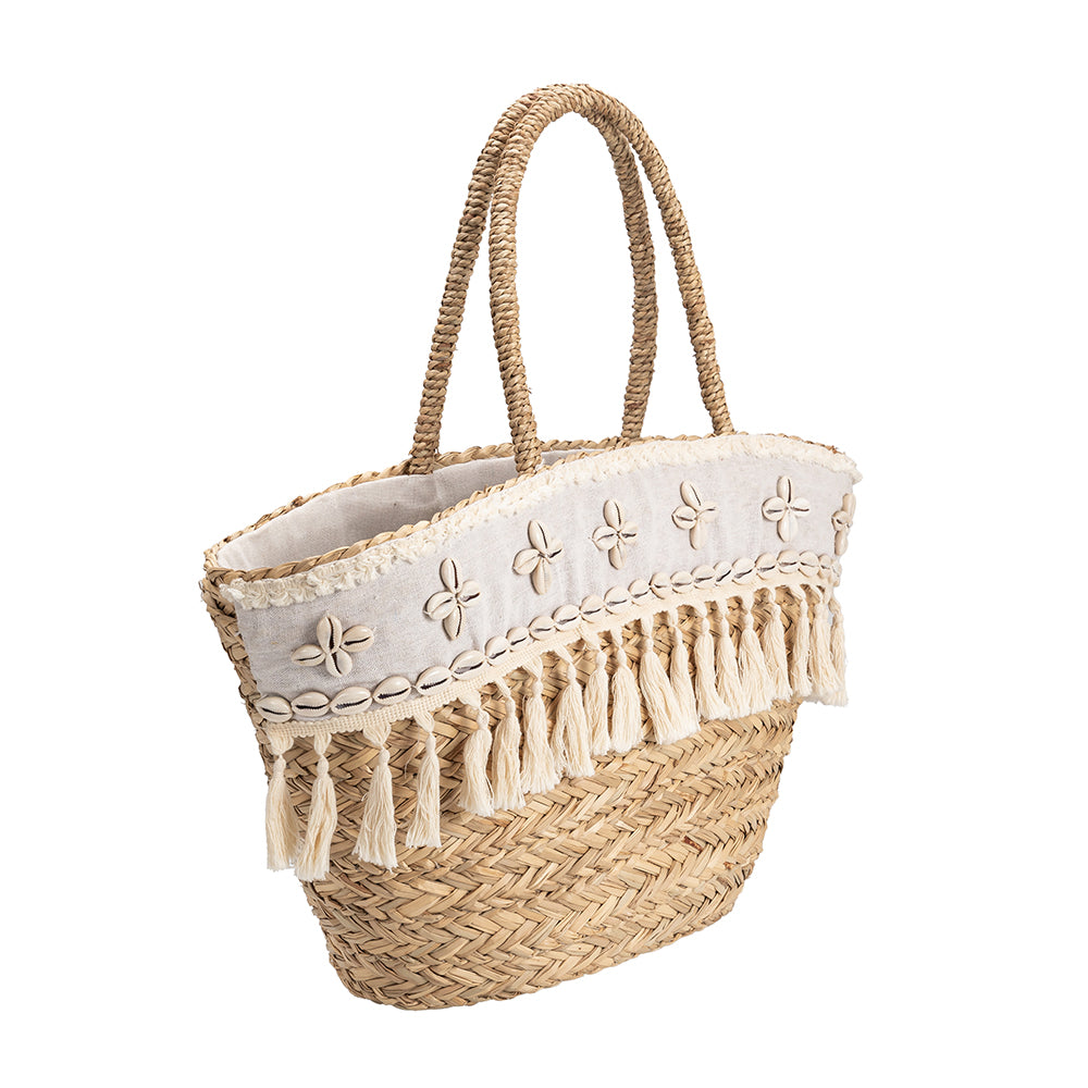 A large straw woven tote bag with seashell details on the front with a drawstring closure.