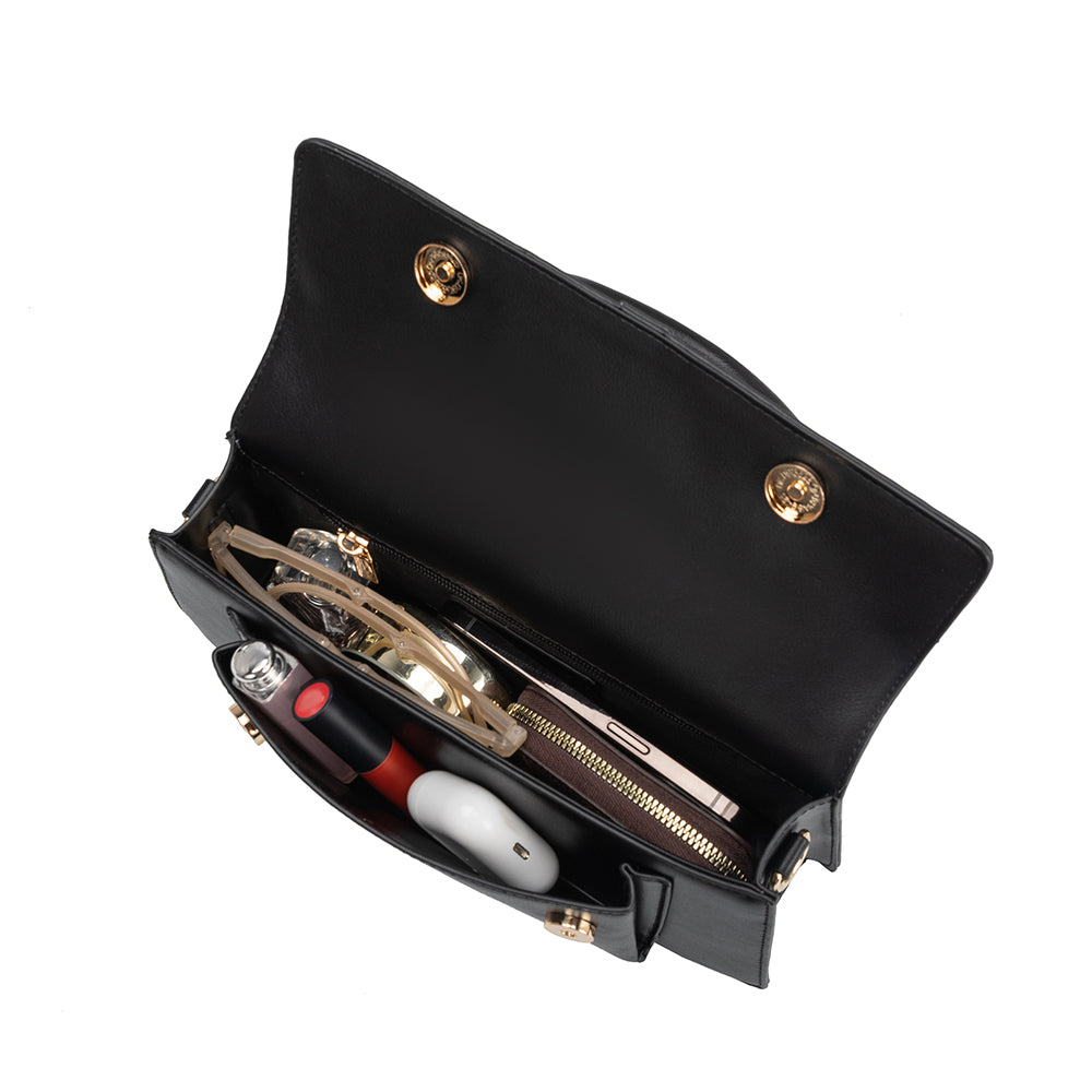 An inside view image of a small rectangle shaped vegan leather top handle bag with a wallet, phone, and makeup inside.