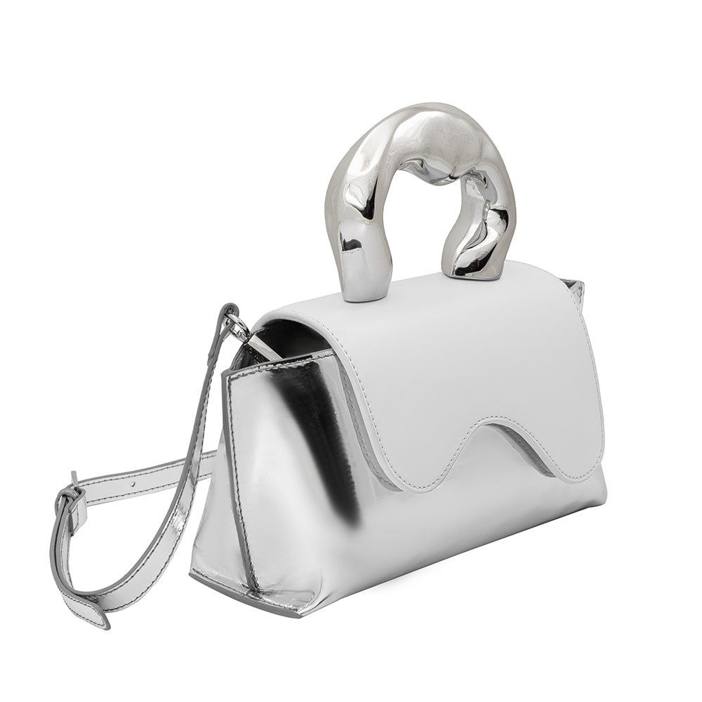 A small metallic and white vegan leather top handle bag with a wavy front flap closure.
