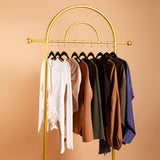 A still image nine different clothing pieces on hangers against an orange background. 
