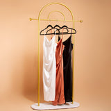 A still image of three cowl neck slip dresses on hangers against an orange background. 