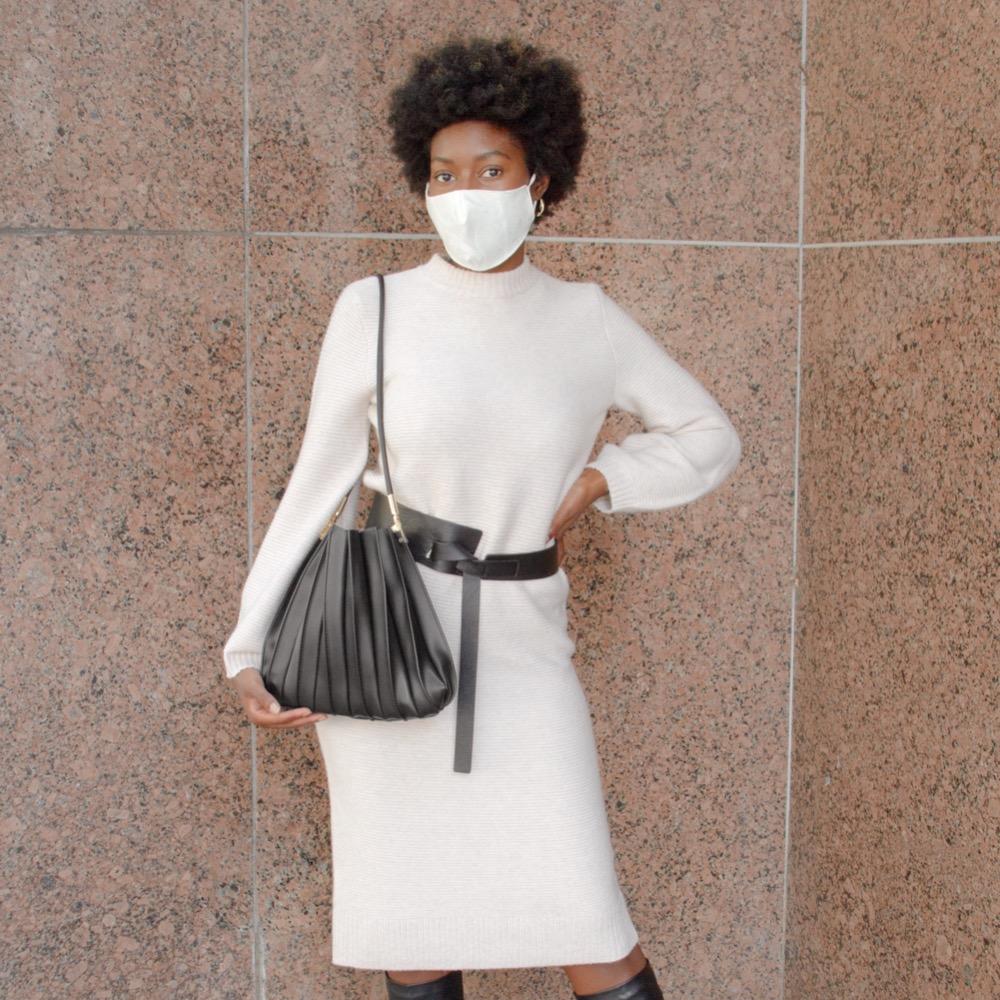 Model wearing black pleated vegan leather shoulder bag.