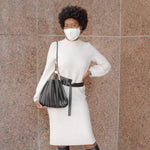 Model wearing black pleated vegan leather shoulder bag.