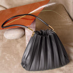 Still photo of a black pleated vegan leather shoulder bag. 
